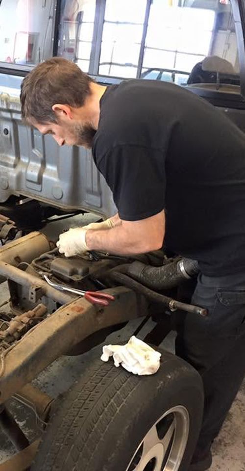 Technician working under a classic truck at Alan Cox Premier Auto Care